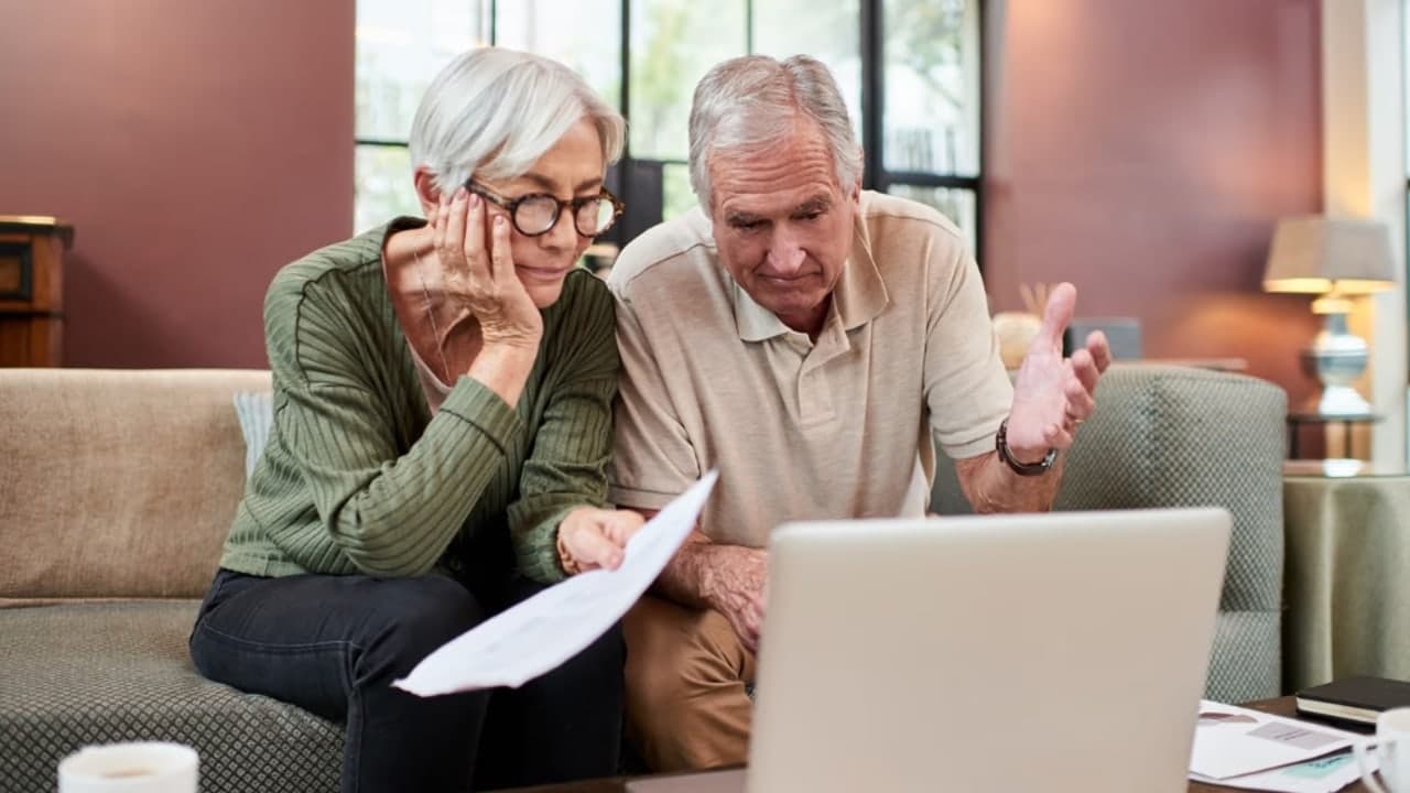 An elderly couple reviewing benefits paperwork at home