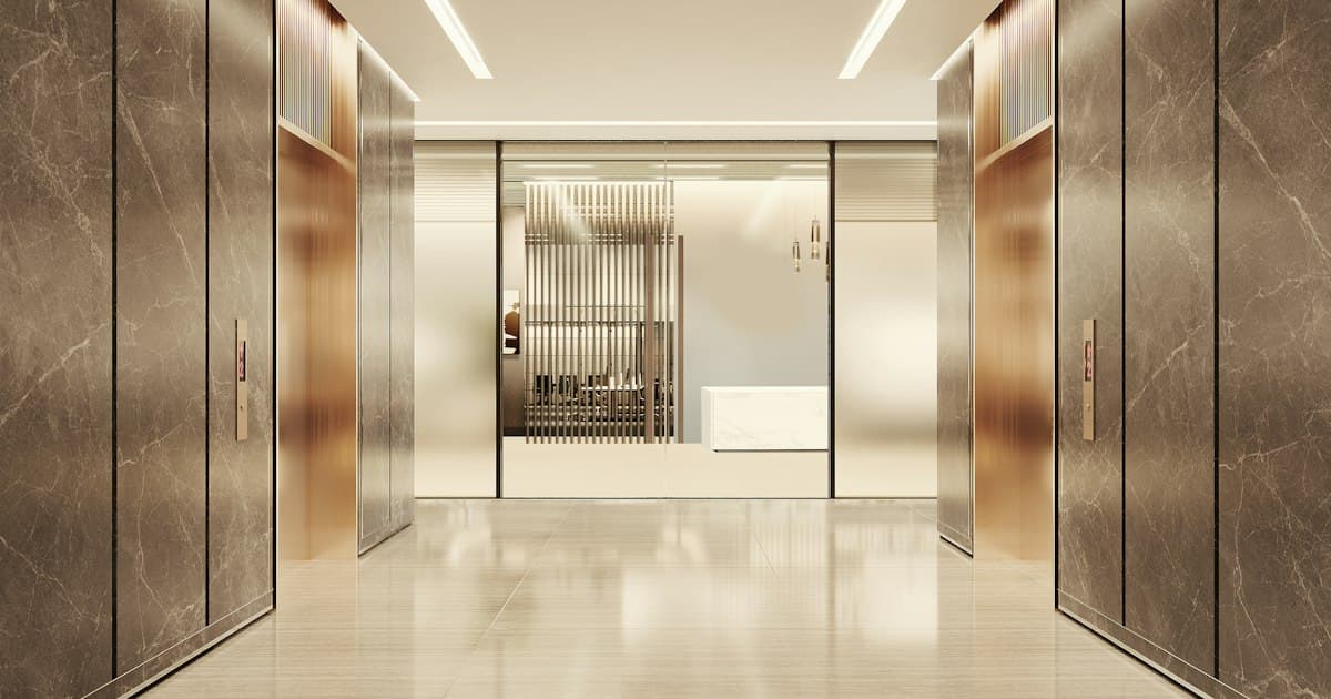 A marble-clad elevator lobby in a professional office building, lit toward frosted glass doors