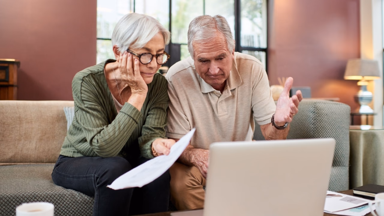 An elderly couple reviewing benefits paperwork at home