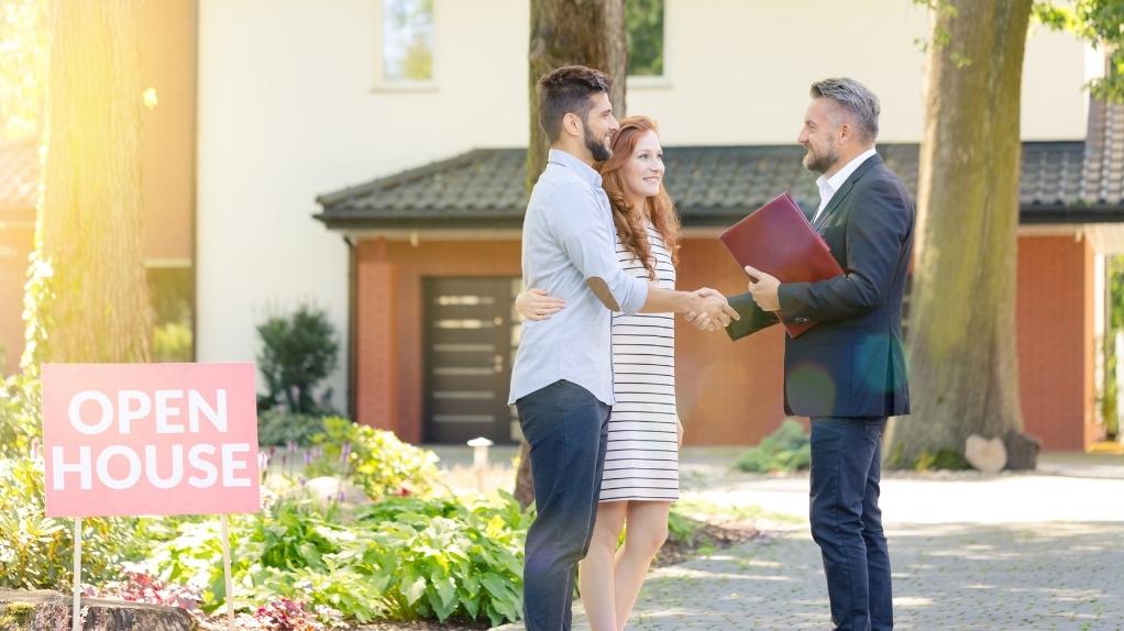 real estate agent shaking hands with a couple after buying a house