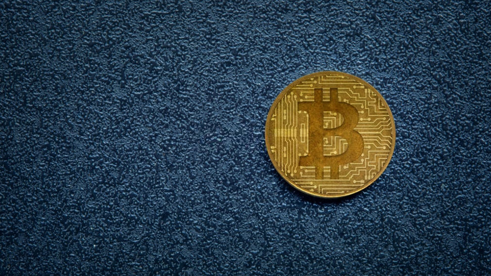 bitcoin logo on a blue background to represent cryptocurrency and banks