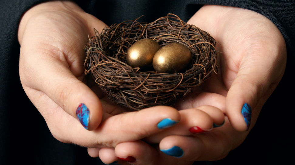hands holding gold eggs in nest