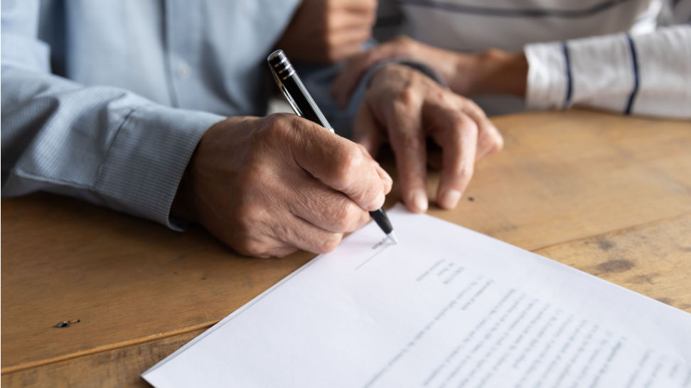 older man putting signature on legal documents