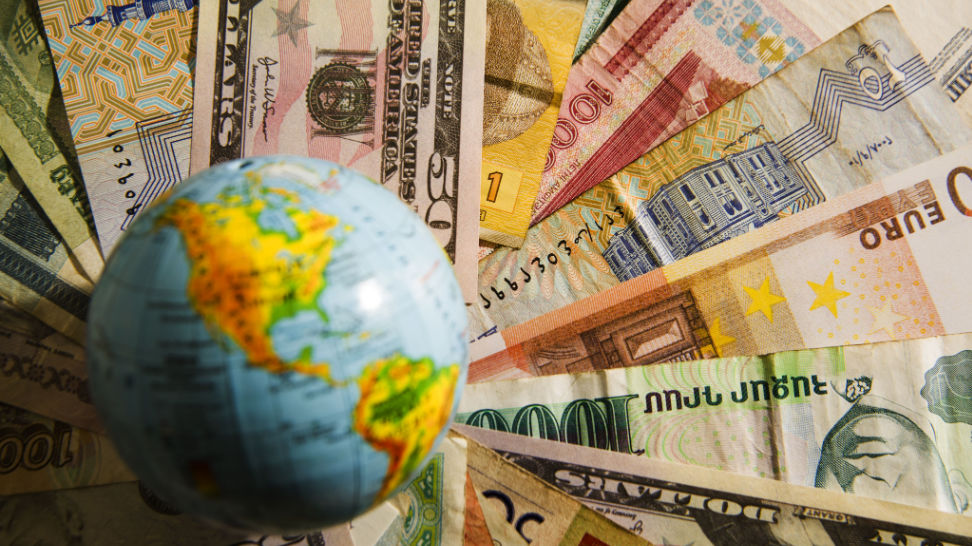 globe map over banknotes of different countries