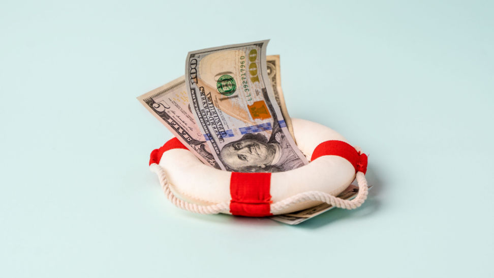 lifebuoy with banknotes lie on blue background