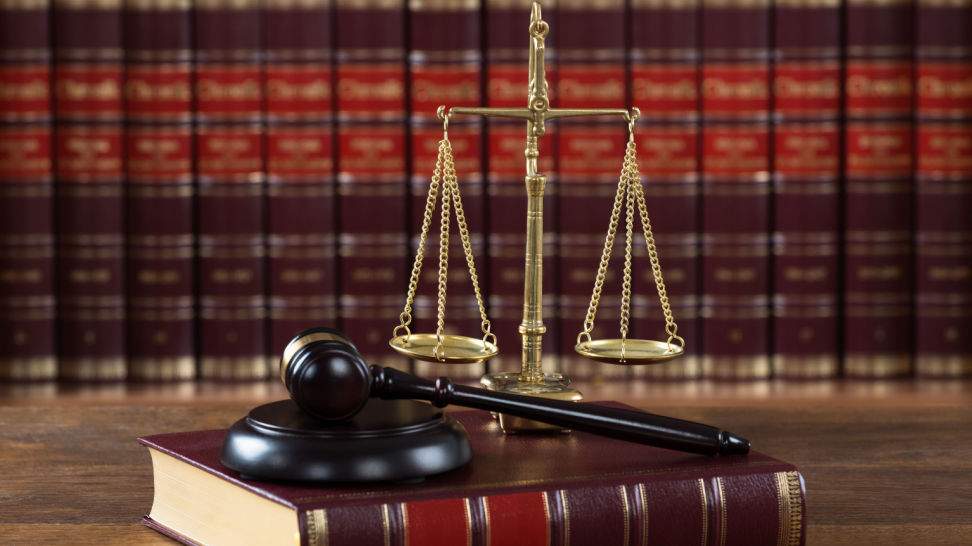 closeup of mallet and legal book with justice scale on table