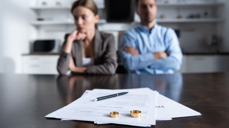 couple sitting at the table with divorce documents and wedding rings