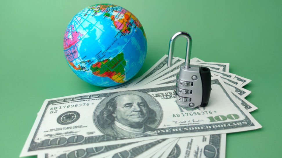 globe dollar bills and open padlock on green background