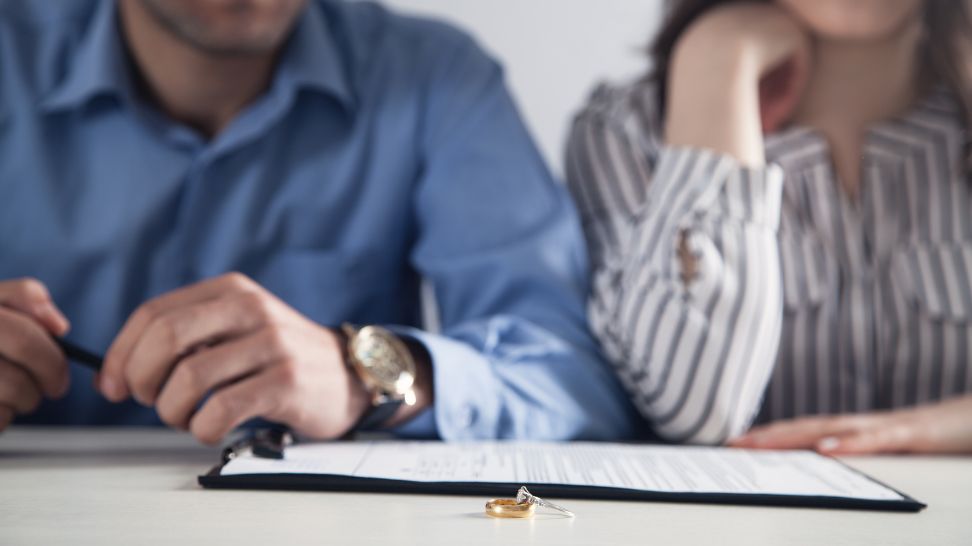 couple with divorce contract and wedding ring on desk