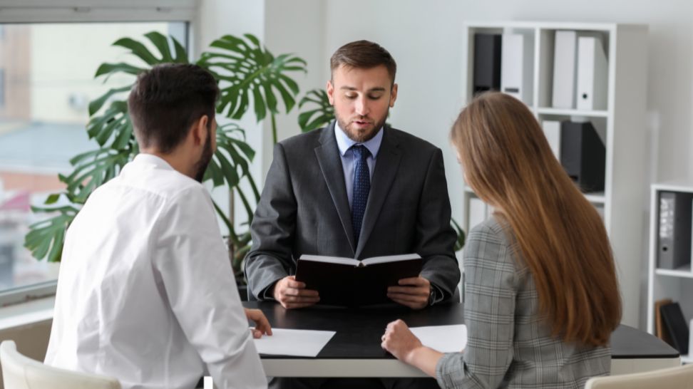 unhappy young couple consulting divorce lawyer in office