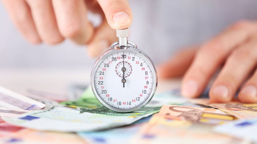 man pressing stopwatch on table with banknotes