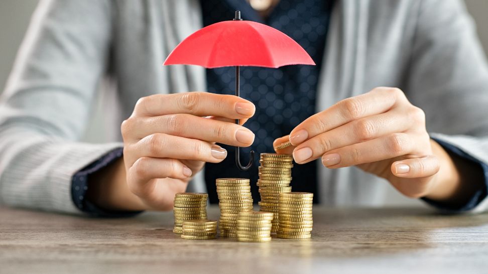 person protecting stacked of coins with an umbrella