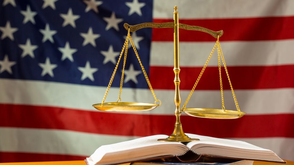 law book and scale of justice on American flag background