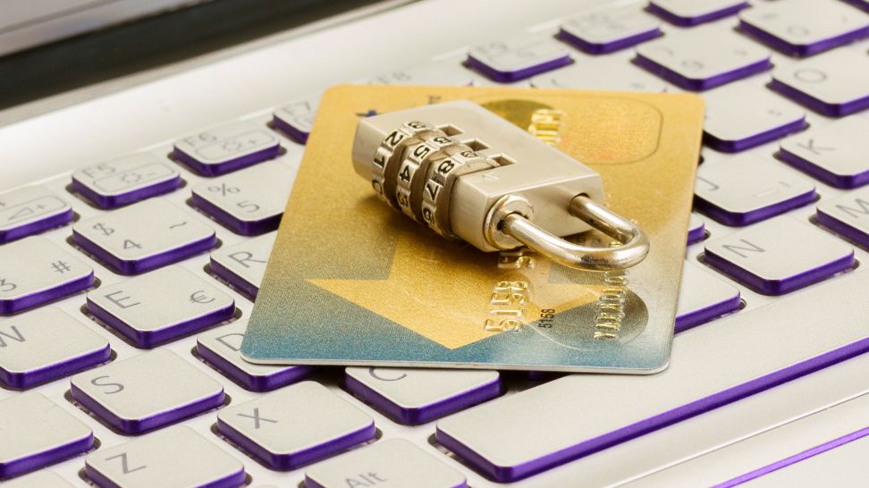 bank card with gold padlock on top of keyboard laptop