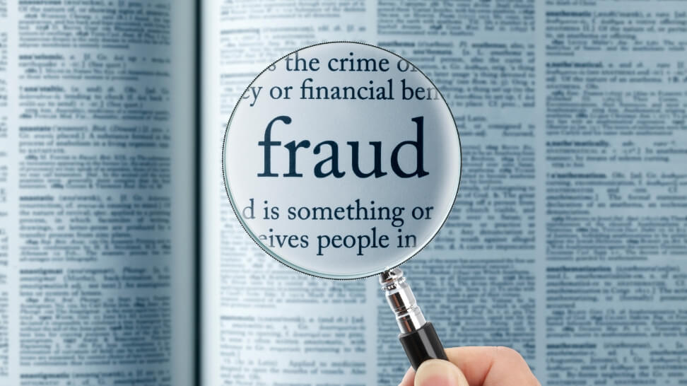 magnifying glass on word fraud in dictionary