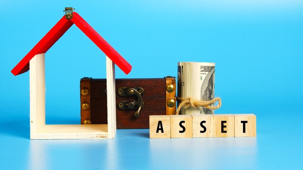 miniature house treasure chest and dollars with mini blocks written asset