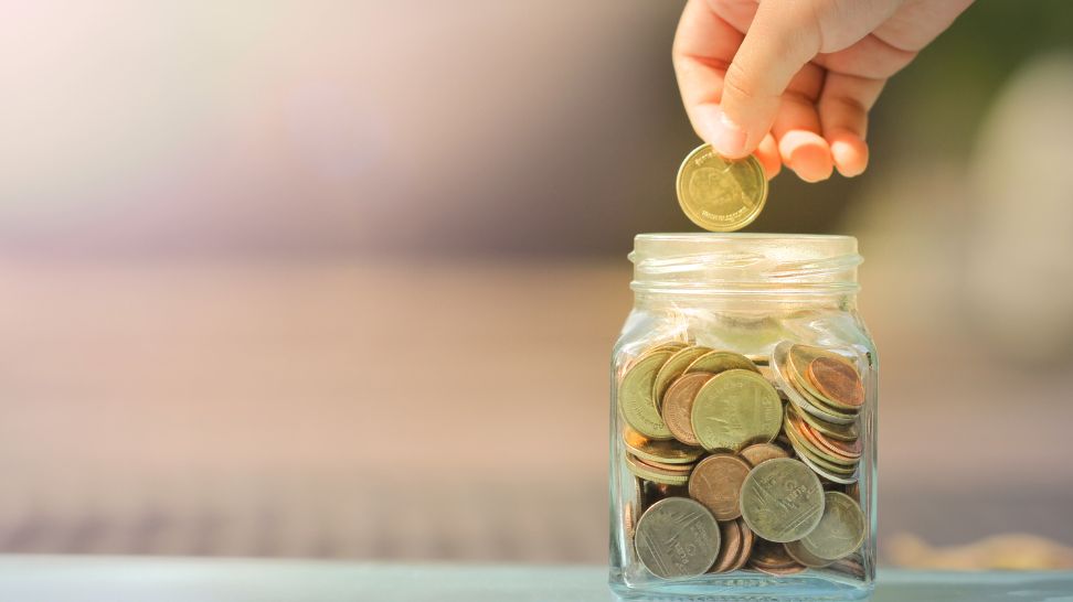 hand is picking coins from jar full of coins