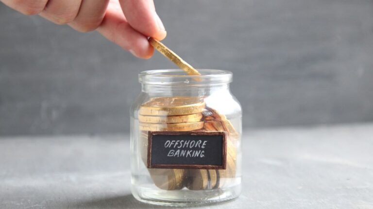 hand putting gold coin in jar filled with coins