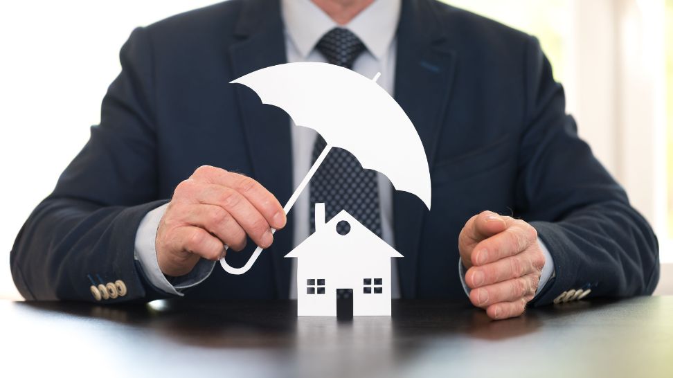 real estate attorney holding umbrella protecting house model