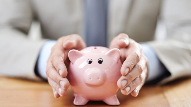 businessman protecting pink piggy bank