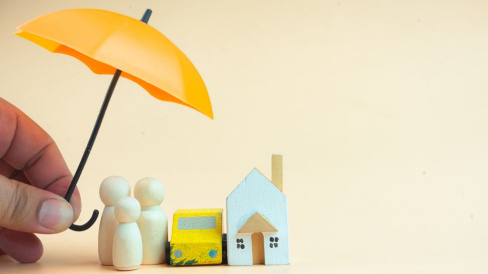 hand holding umbrella protecting human car and house figure