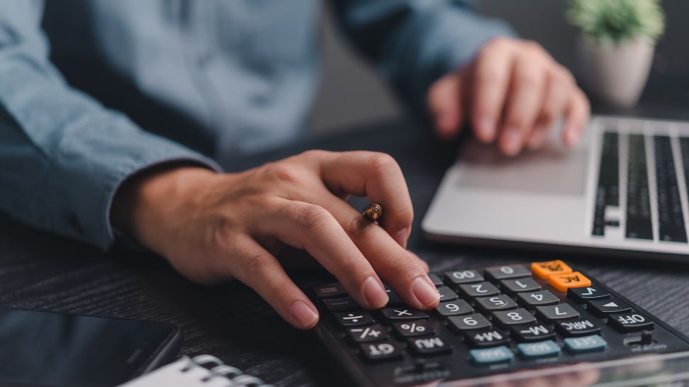 man using calculator and laptop